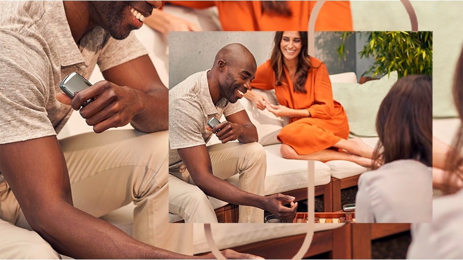 Ploom X životní styl - sedící usměvavá dvojice - žena v oranžových šatech a muž držící Ploom X